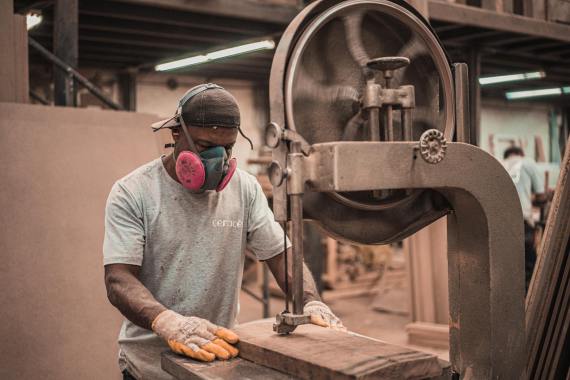 A man cutting wood on a big band saw.