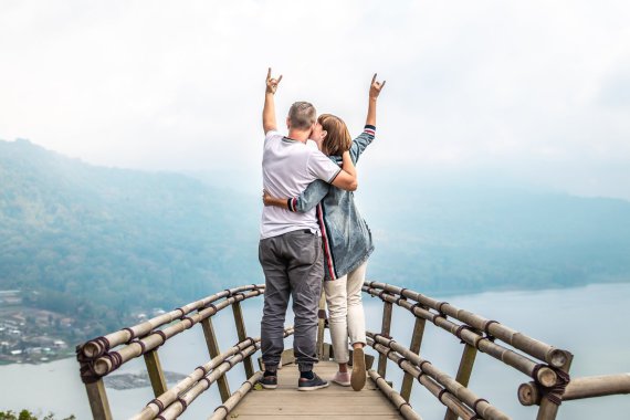 Man and woman together standing on a balcony with their arms in the air.