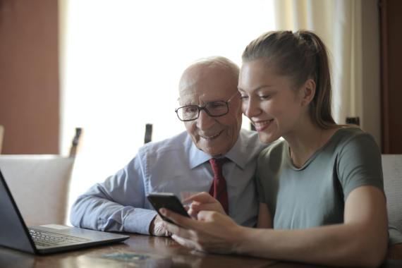 An old man and a young lady learning in front of a laptop.