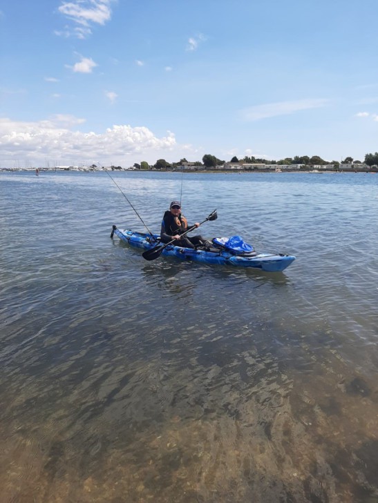 Man rowing a kayak near the shore.