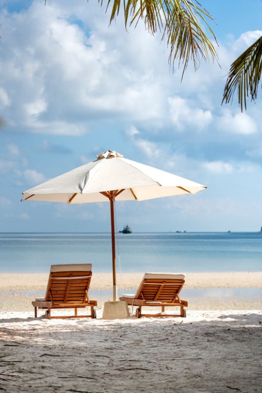 Two deckchairs on a sunny beach.