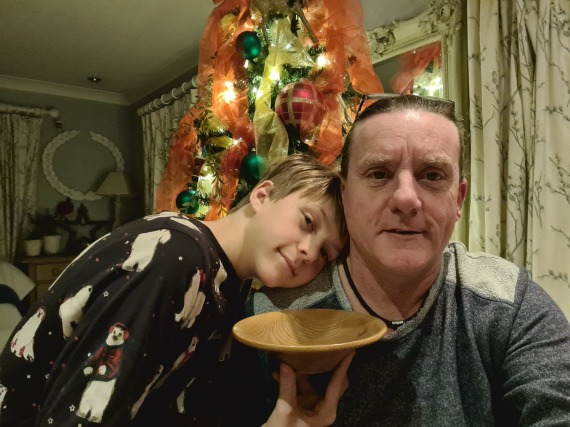 Father and son standing in front of a Xmas Tree with a bowl they had made as a present for an aunty.