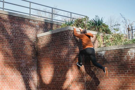 A man trying to climb up a wall using Parcore.